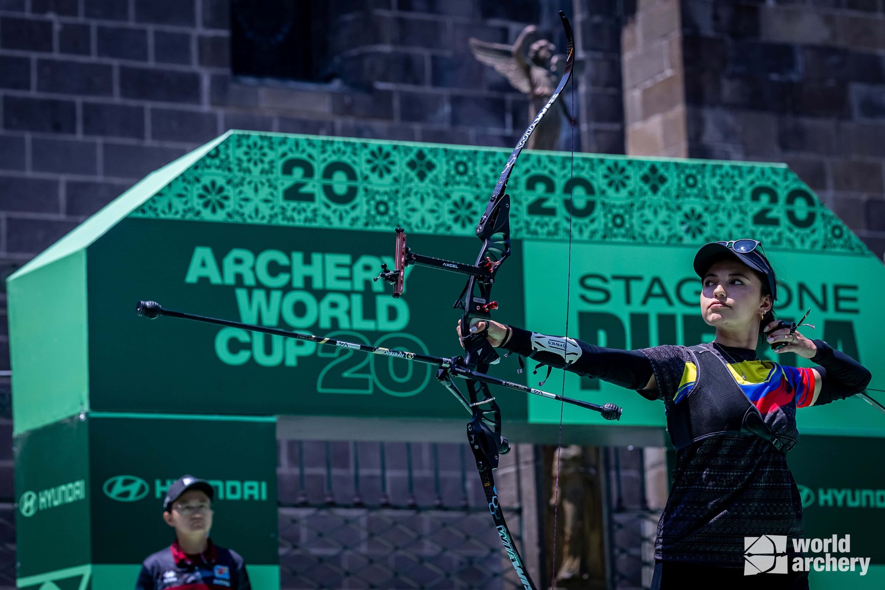 The 2026 identity in a competition setting. Source: Arecibo; stadium photography credited to ALBERGA / WORLD ARCHERY.